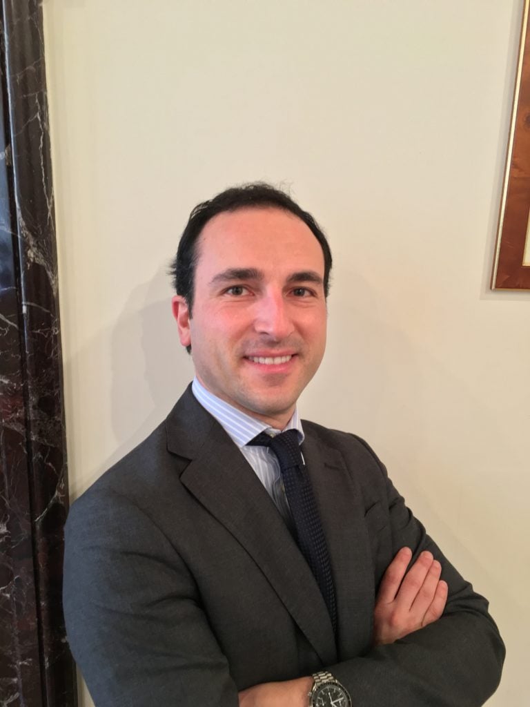 Lawyer posing confidently with arms crossed in a professional office setting.