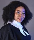 Female lawyer wearing legal robes and a collarette, looking confidently at the camera against a neutral background.