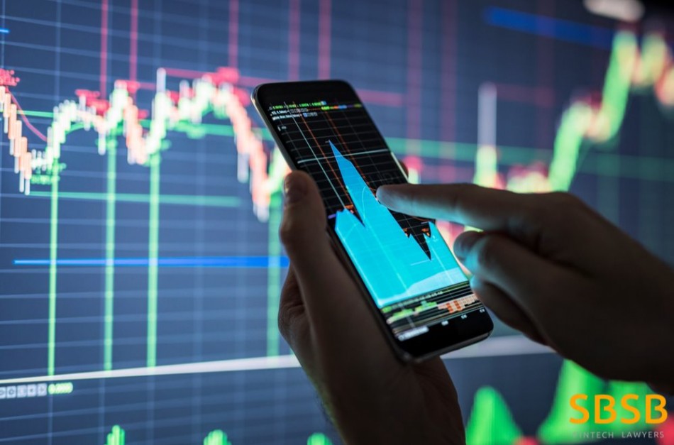 Individual analyzing financial data on a smartphone with stock market graphs in the background.