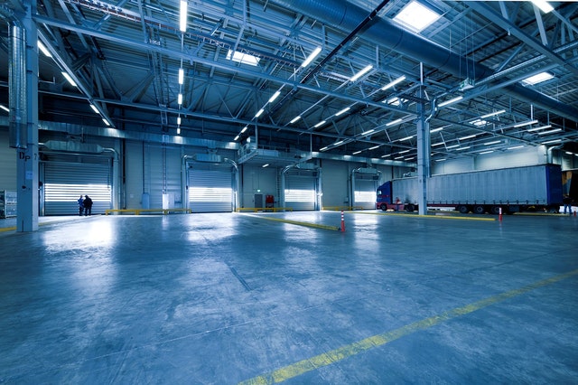 Spacious industrial warehouse interior with loading docks and vehicles ready for transport.