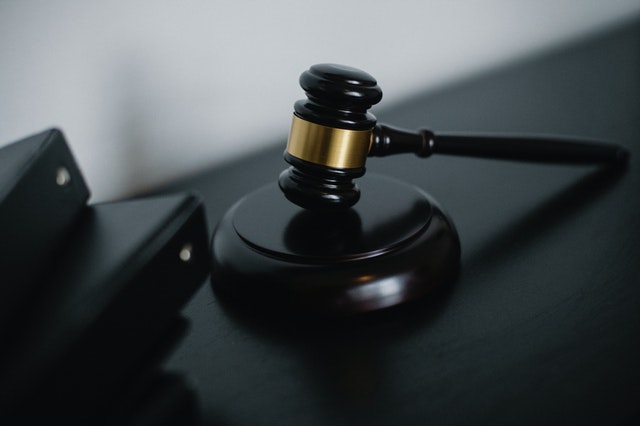 Gavel resting on black desk with legal files in background, symbolizing court proceedings or legal decision-making.