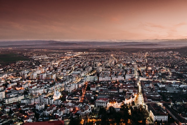 Cityscape view at dusk showing a densely populated urban area with buildings and streets illuminated.
