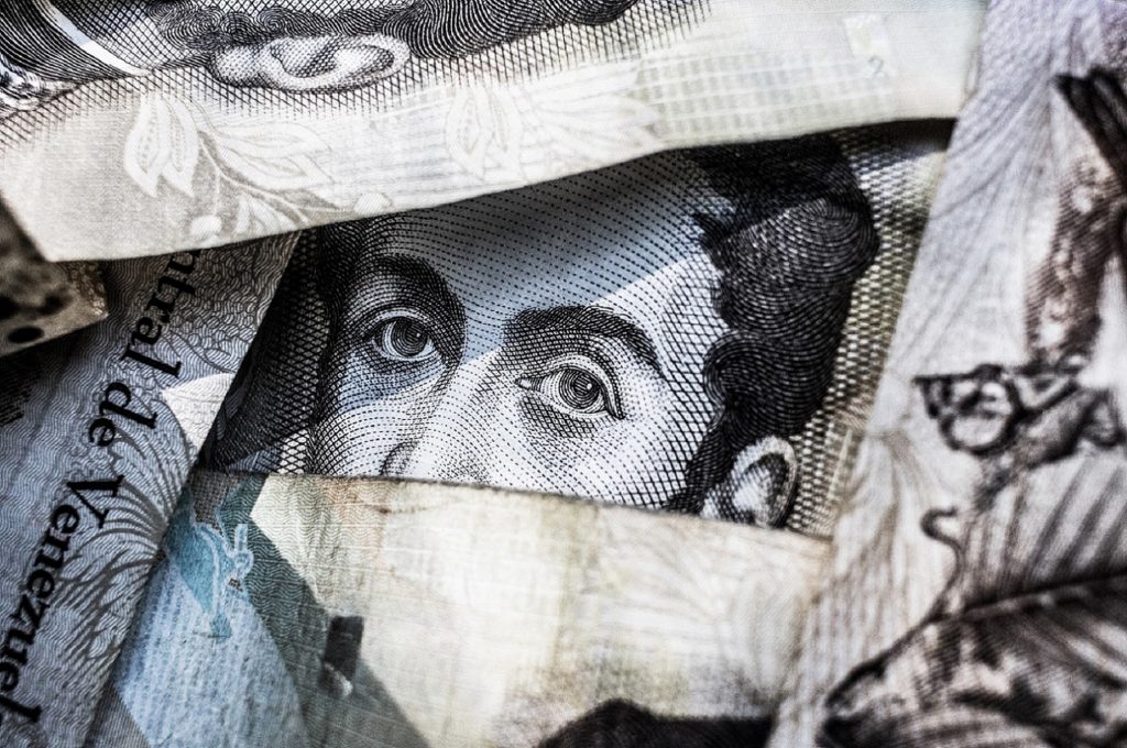 Close-up of Venezuelan banknotes displaying intricate designs and the image of a prominent figure.