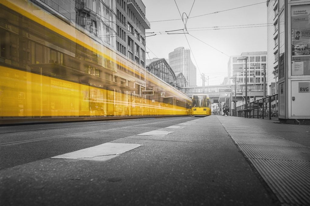 Yellow tram moving along the street in a cityscape with blurred background buildings.