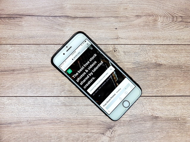 Mobile phone displaying a website with text about free stock photos and videos on a wooden surface.