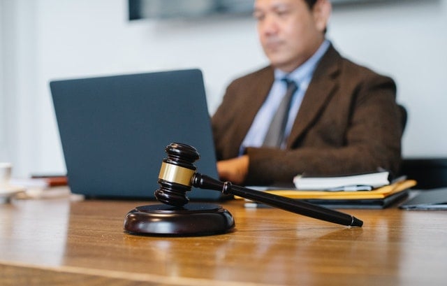 Lawyer working on a laptop at a desk, with a gavel prominently placed in the foreground.
