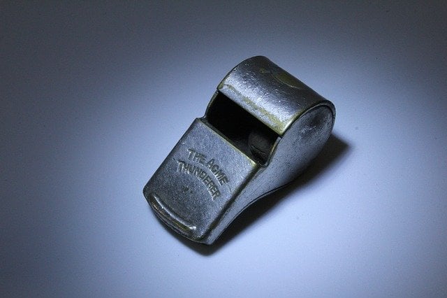 Whistle on a dark surface, possibly for signaling or referee use in sports or legal contexts.