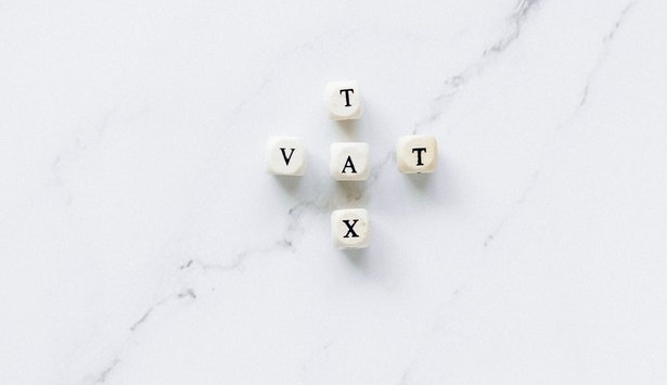 Five dice spelling "T," "A," "X," and "V," arranged on a white marble surface.