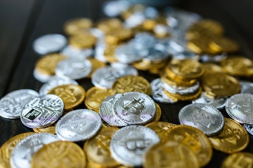 Various cryptocurrencies depicted as gold and silver coins scattered on a wooden surface.