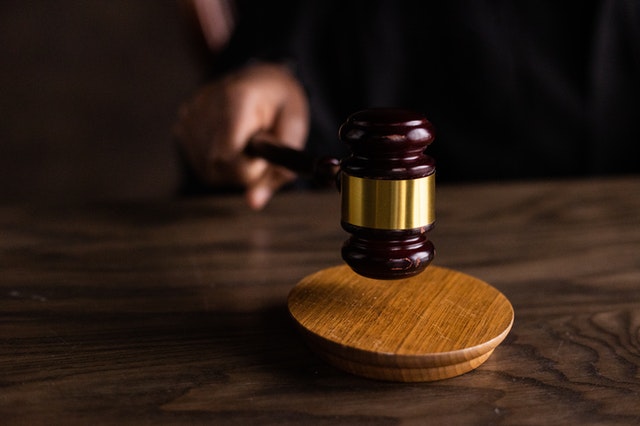 Gavel striking a wooden block, symbolizing a legal decision in a courtroom setting.