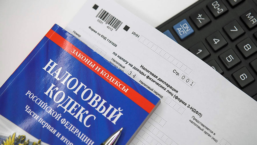 Tax code book, tax declaration form, and a calculator arranged on a desk for legal financial review.