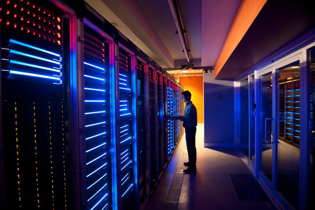 Individual monitoring server equipment in a dimly lit data center with colorful LED lights.