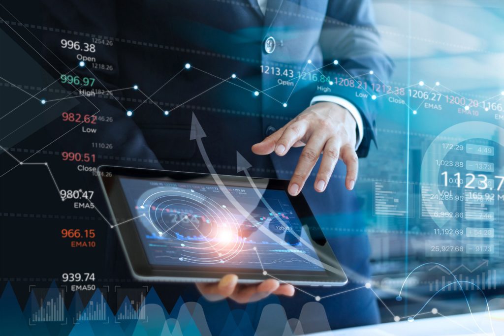 Business professional analyzing data on a tablet with digital financial charts in the background.