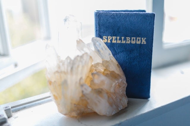 Crystal formation next to a blue spellbook titled "SPELLBOOK" on a windowsill.