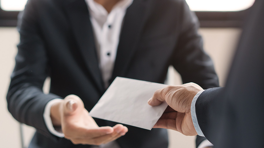 Lawyer handing a sealed envelope to another individual in a professional setting.