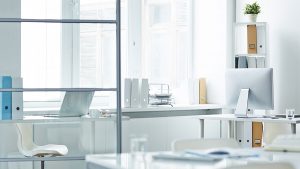 Bright, minimalist law office with desks, a computer, and storage shelves filled with legal documents.