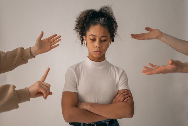 a girl with her arms crossed surrounded by hands