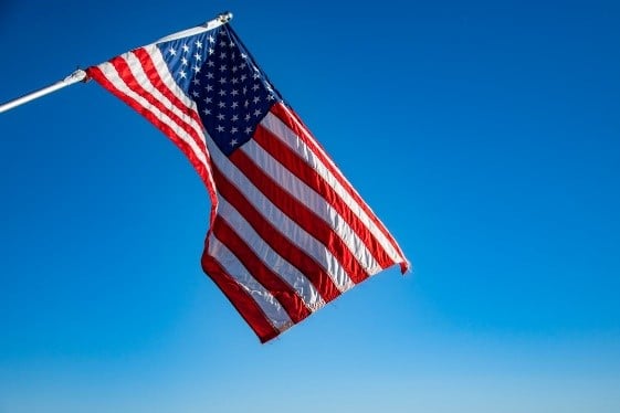 American flag waving against a clear blue sky.