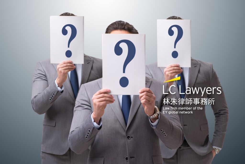 Three professionals in suits holding blank signs with question marks in front of their faces in a neutral setting.
