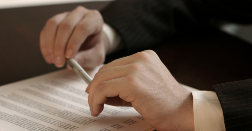 Attorney holding a pen while reviewing legal documents on a desk.