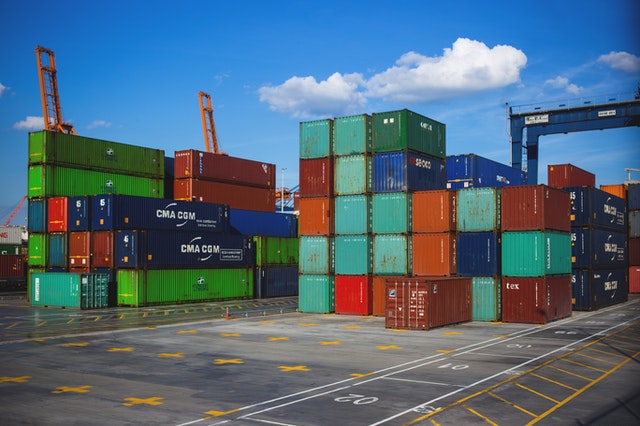 Container yard with stacked shipping containers in various colors under a clear blue sky.