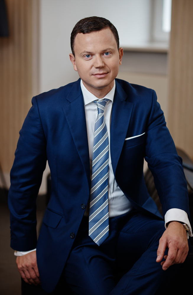 Lawyer in a blue suit seated in an office, looking directly at the camera with a professional demeanor.