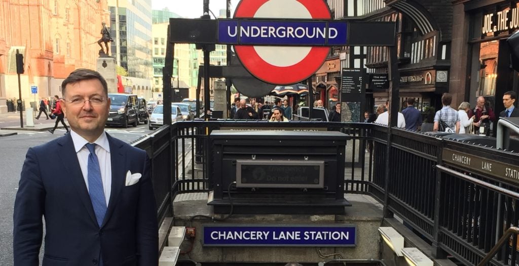 Lawyer standing in front of Chancery Lane Underground Station in a bustling urban environment.