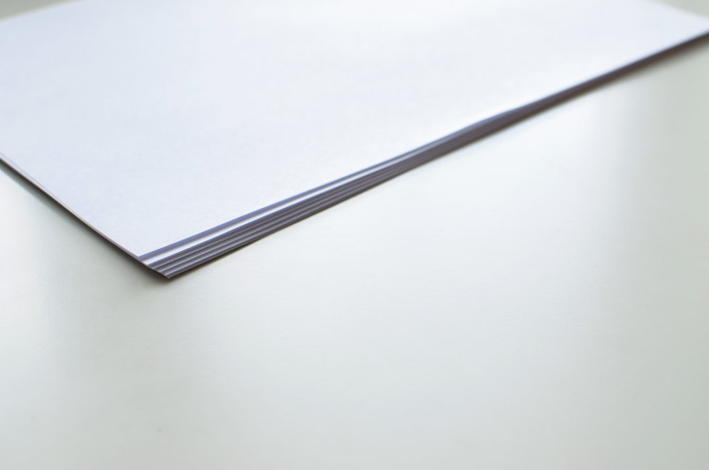 Stack of blank sheets of paper on a smooth surface, often used for legal document preparation or notes.