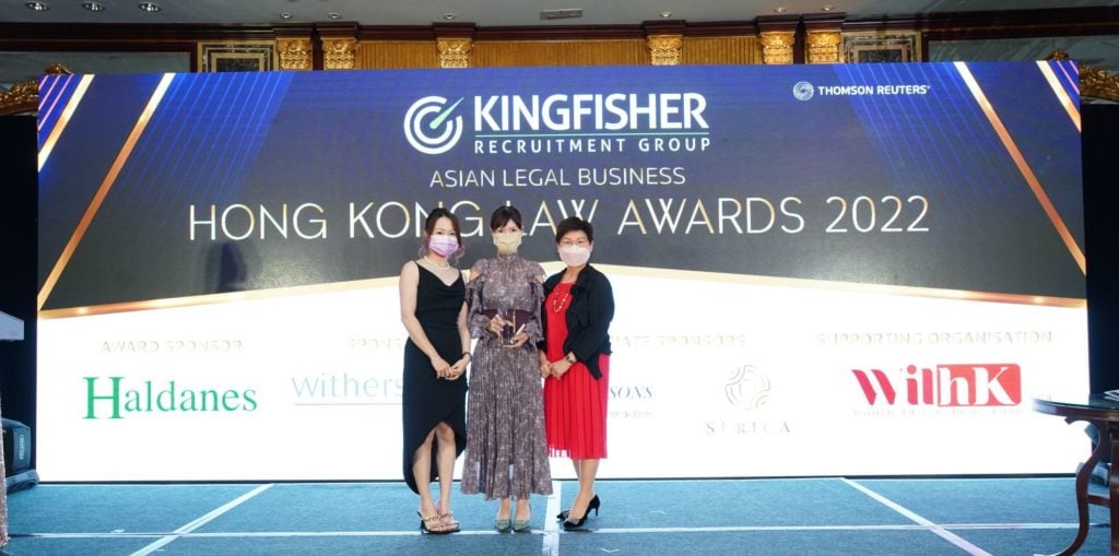 Three women posing with an award at the Hong Kong Law Awards 2022 event.