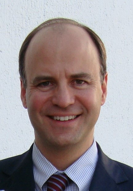 Lawyer smiling in a suit against a plain background.