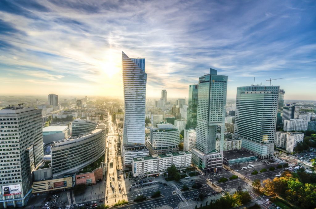 City skyline featuring modern skyscrapers and busy streets under a clear sky at sunset.