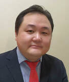 Lawyer posing for professional profile photo in a suit with a red tie against a neutral background.