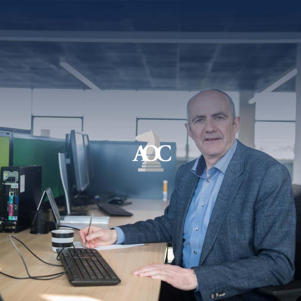 Legal professional seated at a desk, reviewing documents with computer monitors in a modern office setting.