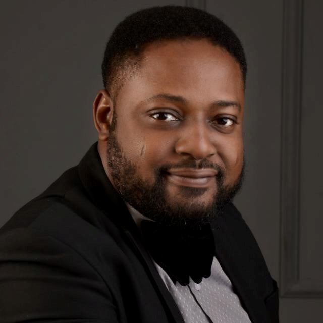 Professional man in formal attire, smiling against a neutral backdrop, possibly a lawyer or legal consultant.