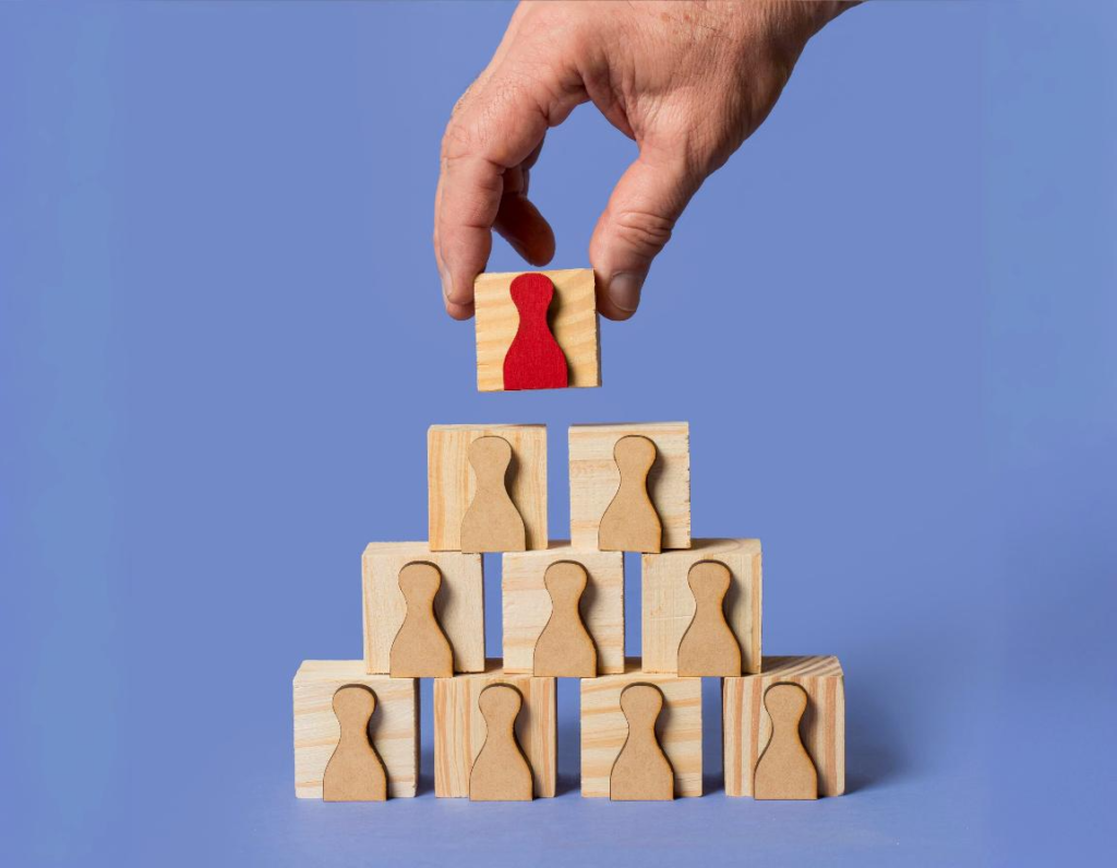 Hand-arranging-wooden-blocks-representing-people-in-a-pyramid.png