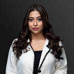 Aisha Khan - Professional woman in a white blazer posing against a dark background, suggesting a formal legal context.
