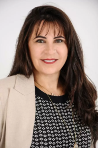 Legal professional with long dark hair, wearing a blazer, and smiling against a plain background.