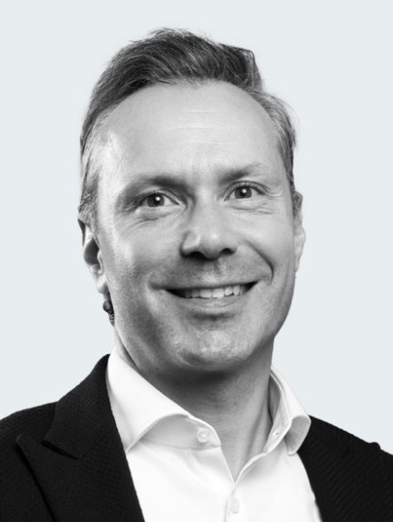 Professional man smiling, dressed in a suit against a light background.