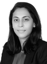 Professional woman in a blazer, seated and looking confidently at the camera, likely an attorney or legal consultant.