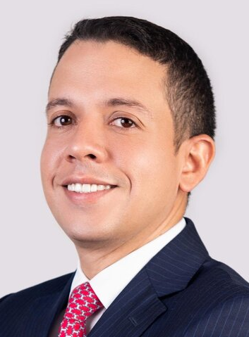Professional lawyer in a suit with a confident smile, posing for a formal headshot against a neutral background.