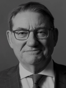 Legal professional with glasses and a suit, presenting a confident expression in neutral background.