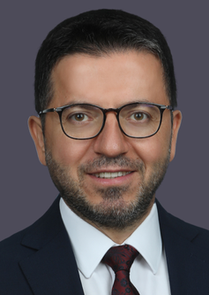 Lawyer in formal attire, wearing glasses, with a neutral expression against a plain background.