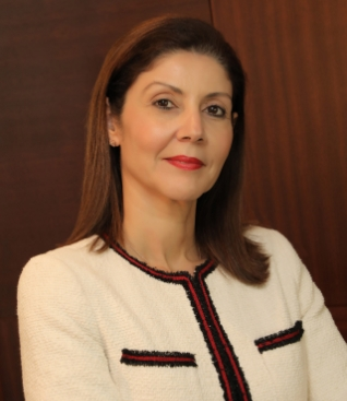 Professional woman in a tailored suit, posed confidently in an office setting, representing a legal professional.