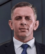 Legal professional in a suit, standing confidently against a modern building backdrop.