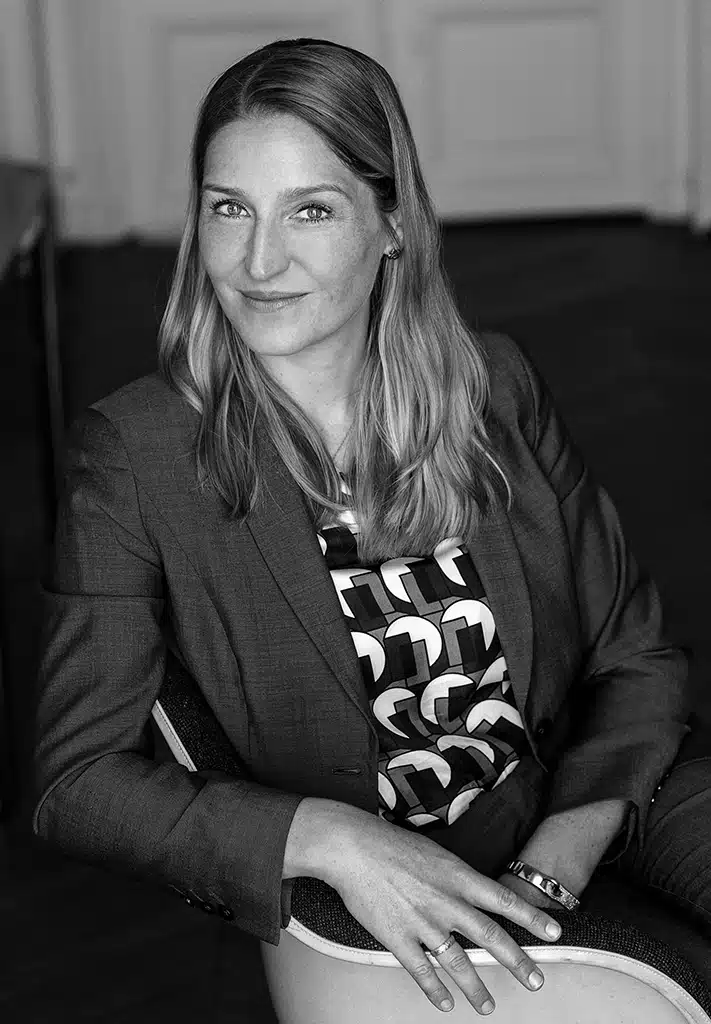 Lawyer posing confidently in professional attire, seated in a legal office setting.