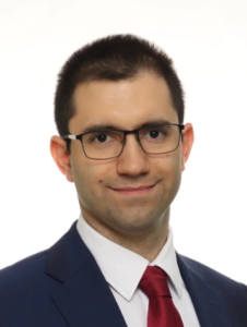 Professional lawyer in a suit and tie, smiling and wearing glasses, suitable for a legal directory profile.