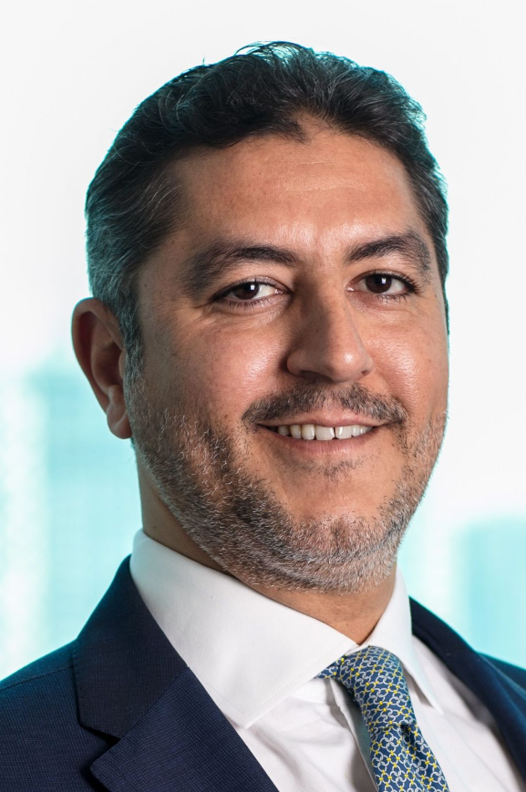 Lawyer smiling confidently in a professional suit against a blurred office background.