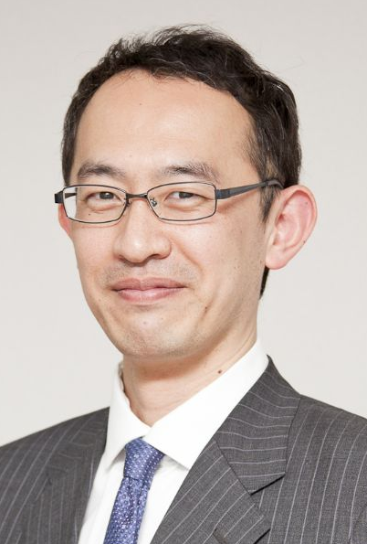 Lawyer in a striped suit and glasses, smiling against a neutral background.