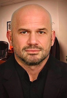 Lawyer posing for professional portrait in an office setting with furniture visible in the background.