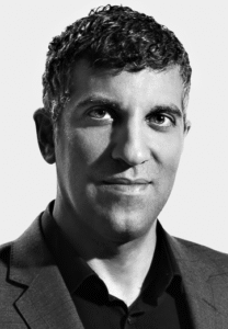 Legal Professional With Short Dark Hair, Wearing A Suit, Posing With A Neutral Expression Against A Light Background.